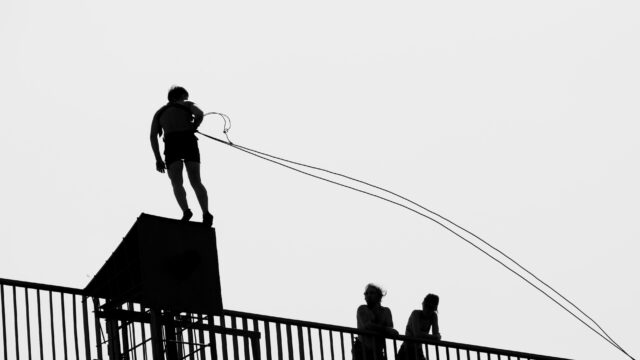 Construction worker attaching lanyard to certified roof tie-off anchor