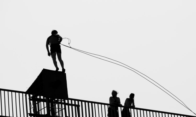 Construction worker attaching lanyard to certified roof tie-off anchor