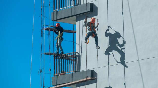 Worker tied to roof harness anchor on flat industrial roof