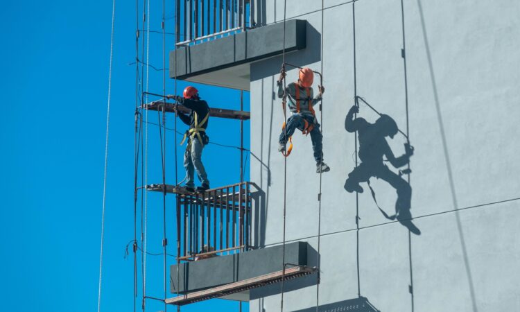 Worker tied to roof harness anchor on flat industrial roof