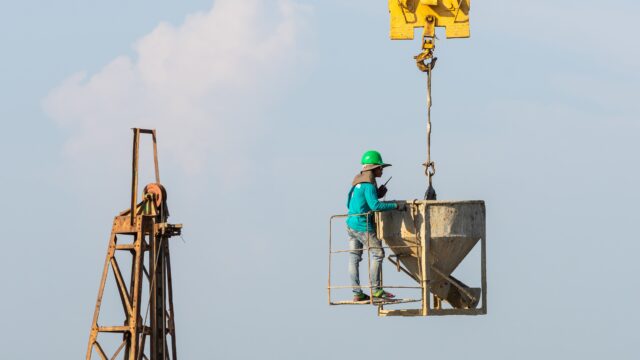 Worker using portable fall protection anchor on metal rooftop