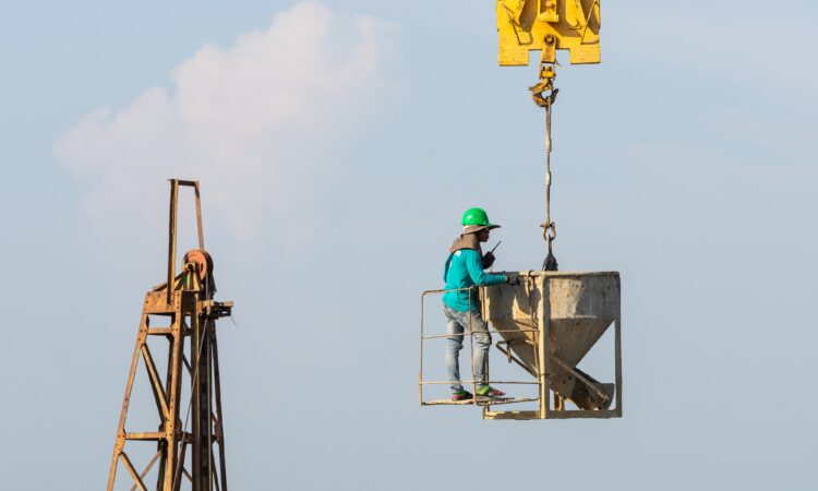 Worker using portable fall protection anchor on metal rooftop